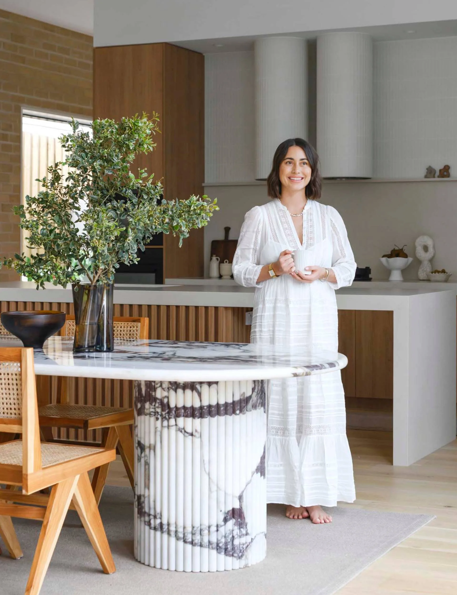 Mid-century-inspired home owner Lead holding a mug beside the dining room table