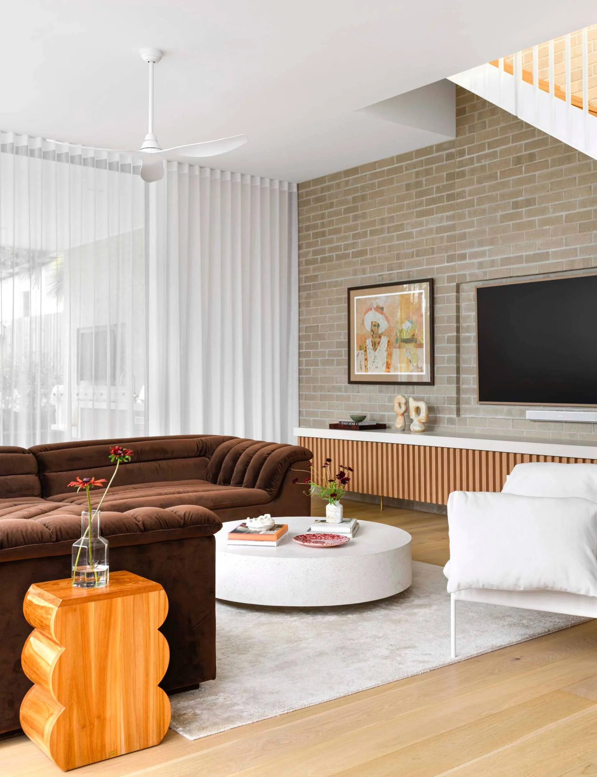 A brown couch and white armchair in a brick living room