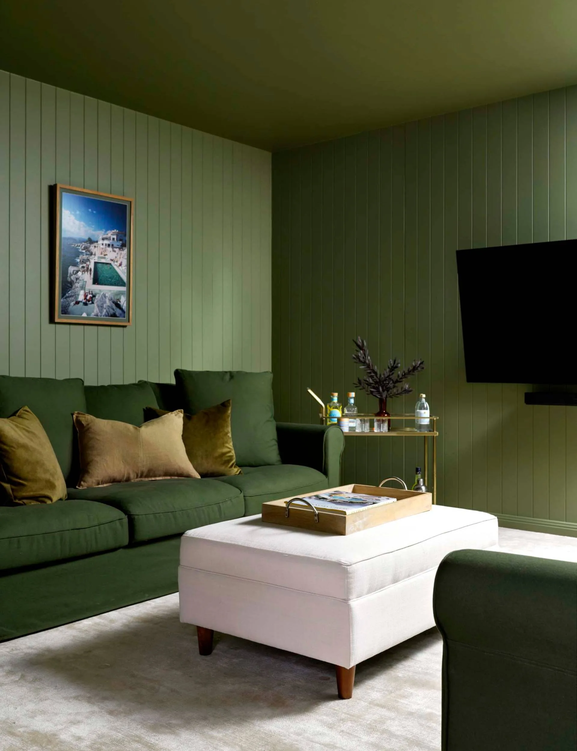 Olive and white furniture in an olive painted mid-century-inspired underground media room