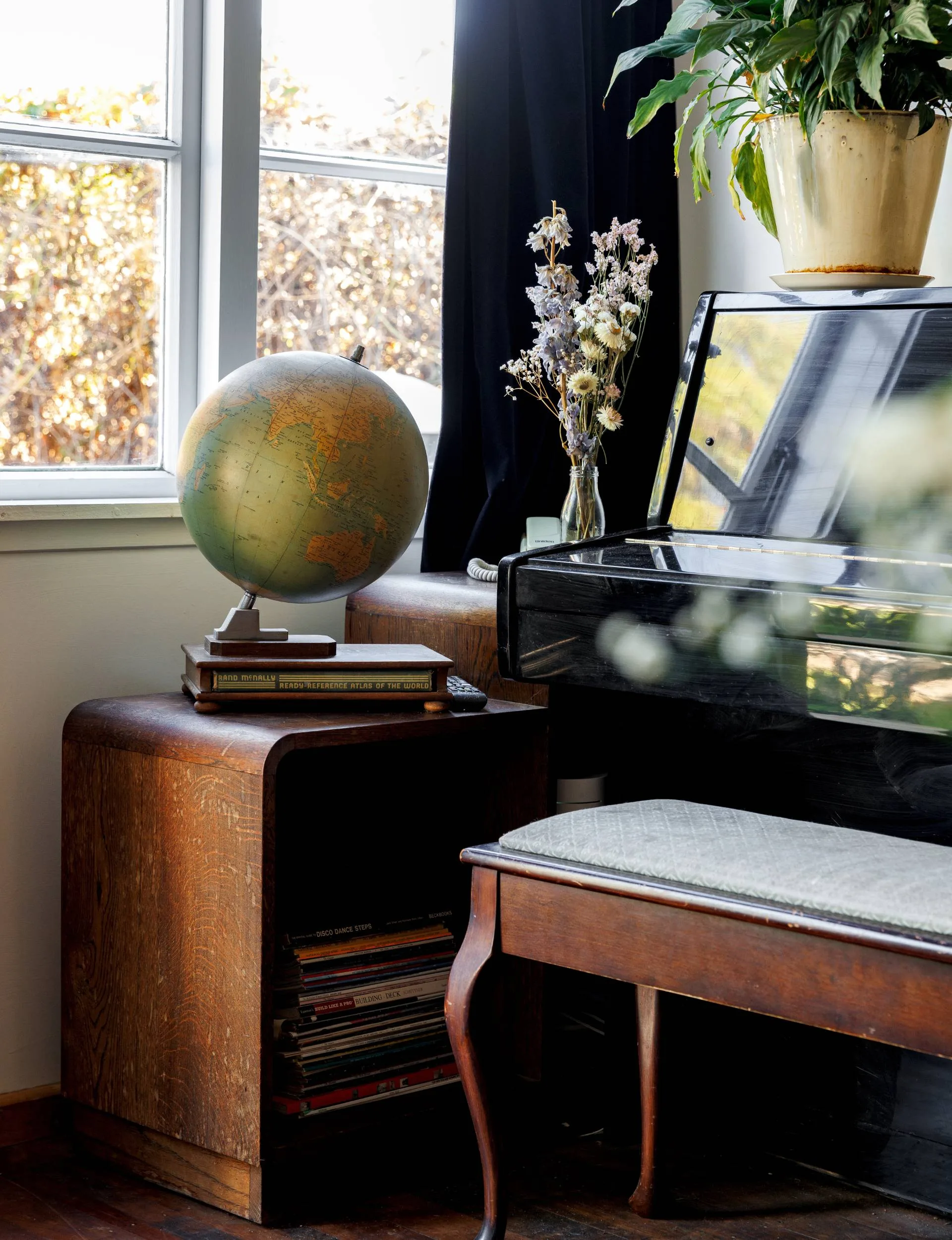Her piano beside a thrifted bookshelf