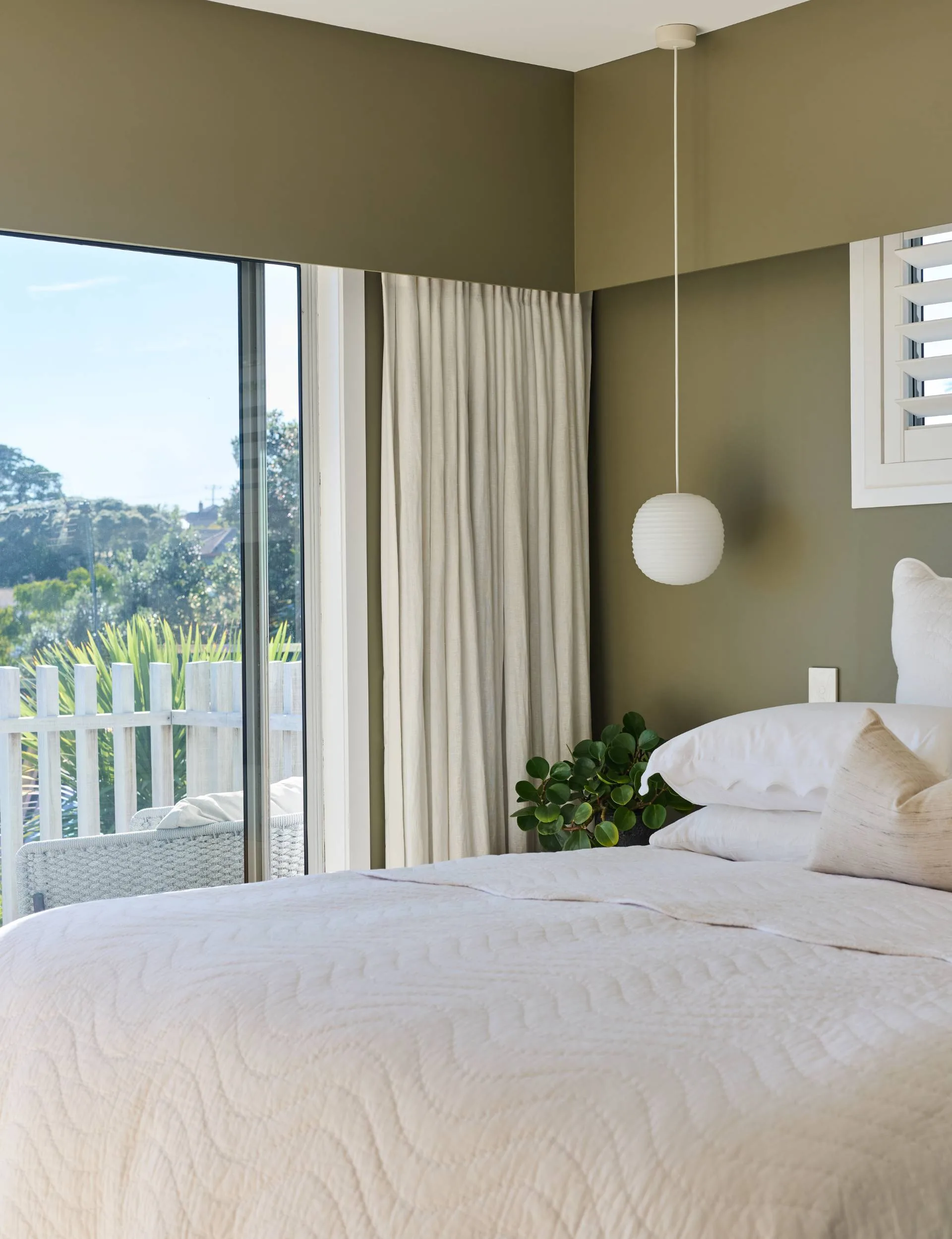 An olive green master bedroom with white accents and bedding