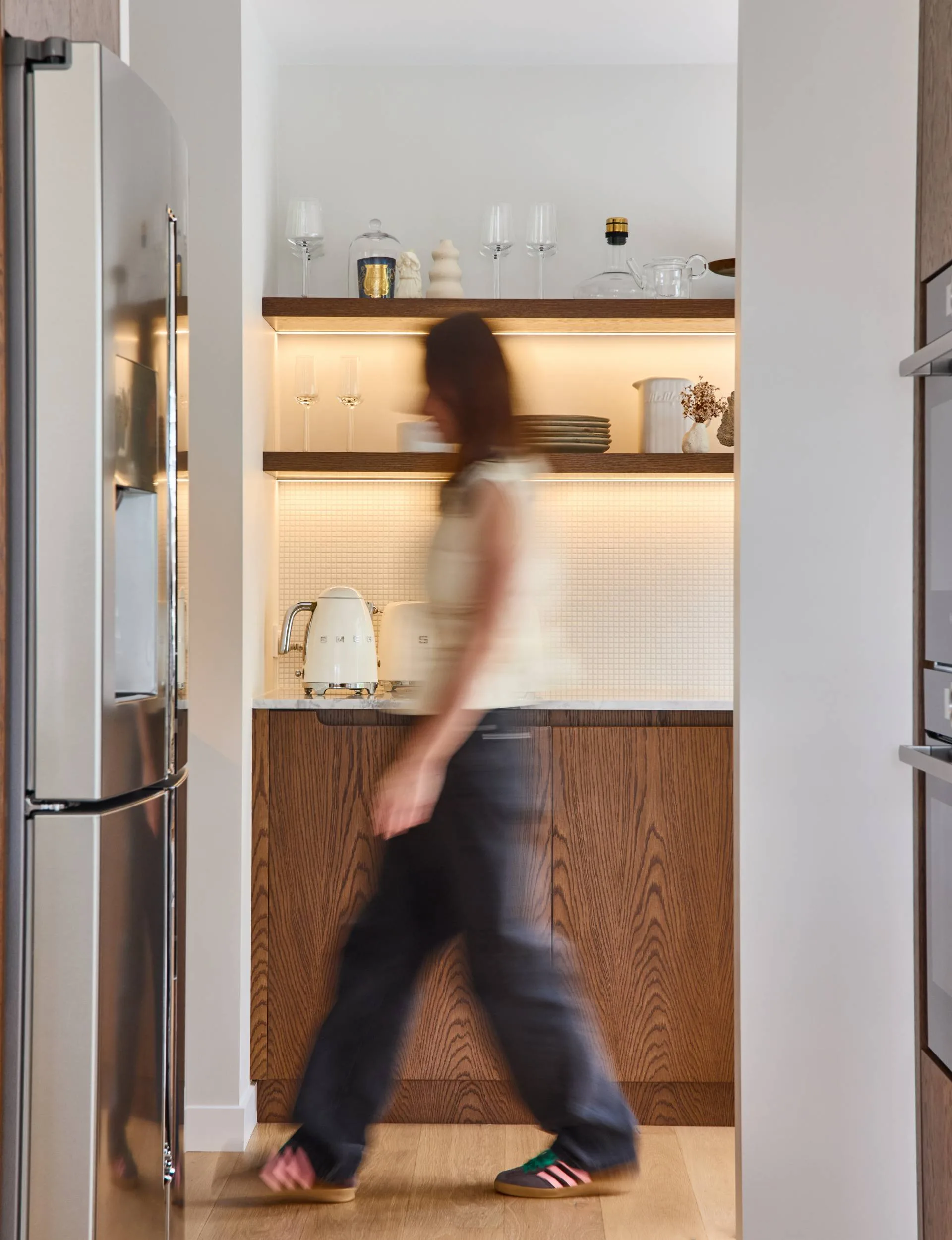 70s home owner Sian walking through her kitchen