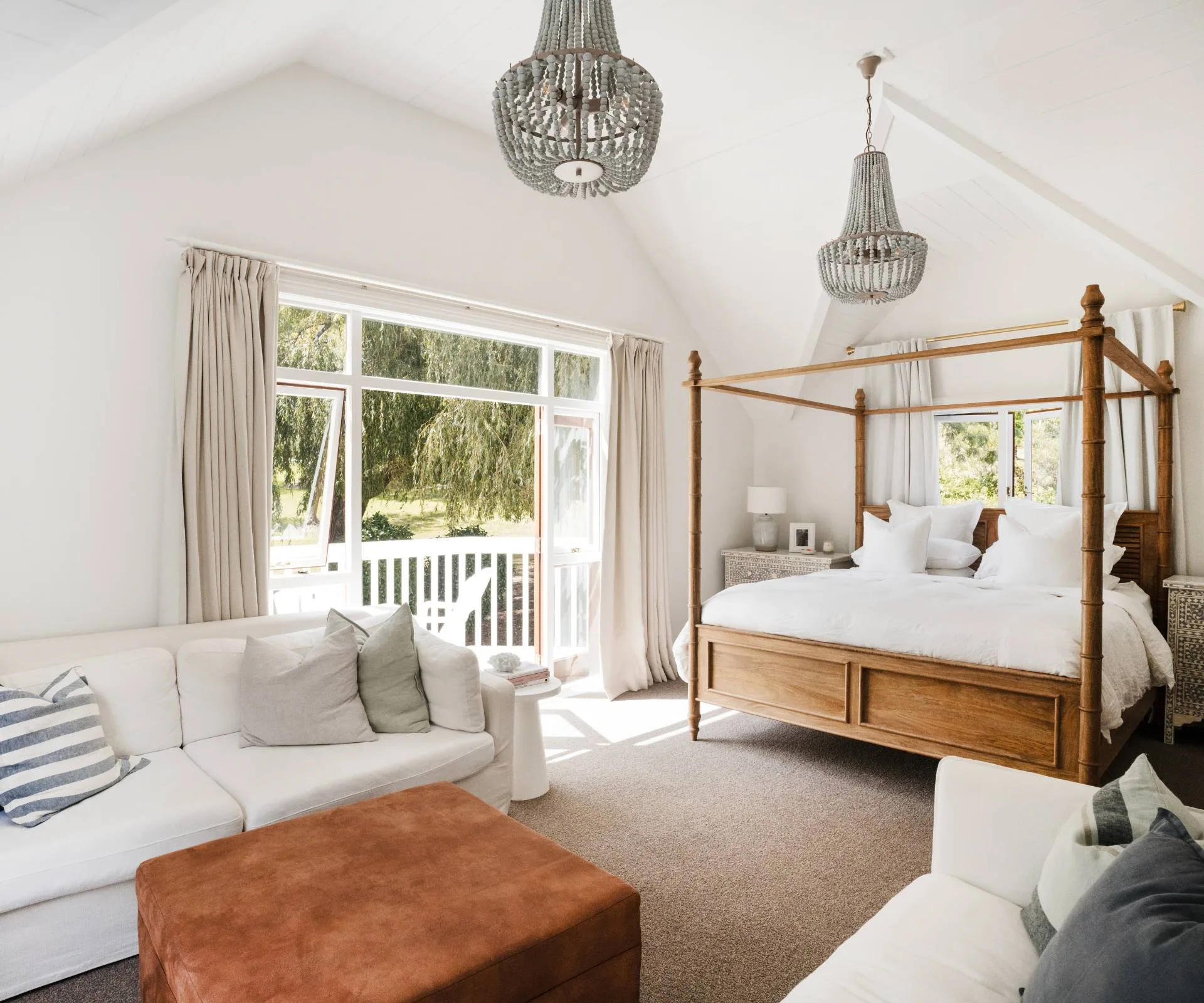 The Auckland homestead master bedroom with a white couch and brown ottoman at the end of the bed