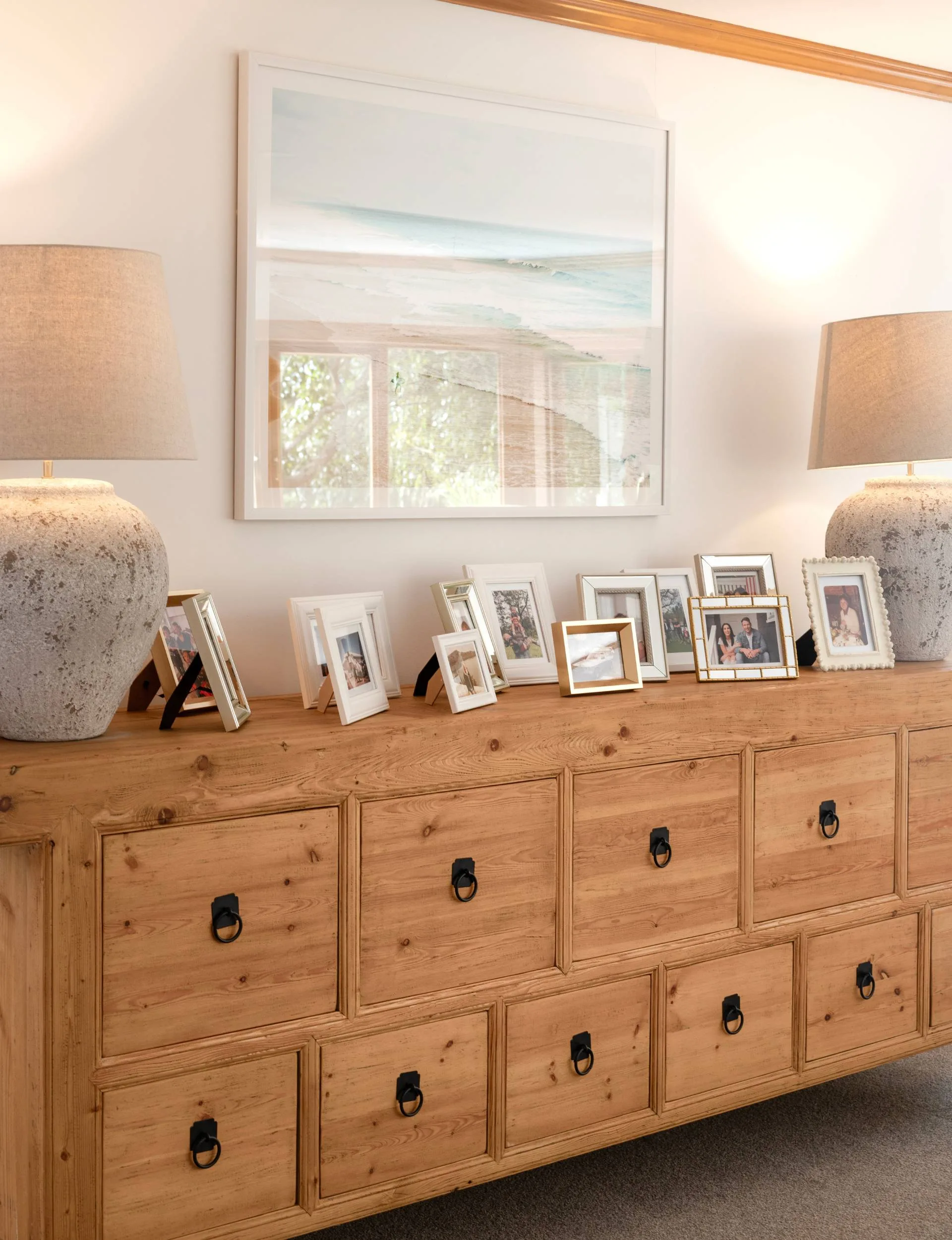 Photos of the family between two vintage lamps on a wooden dresser