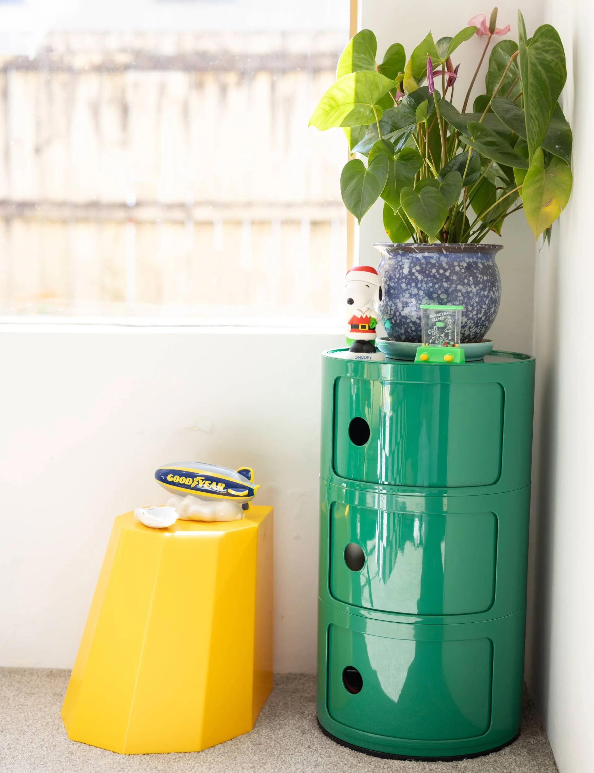 A green barrel cabinet and yellow circus stool in a corner