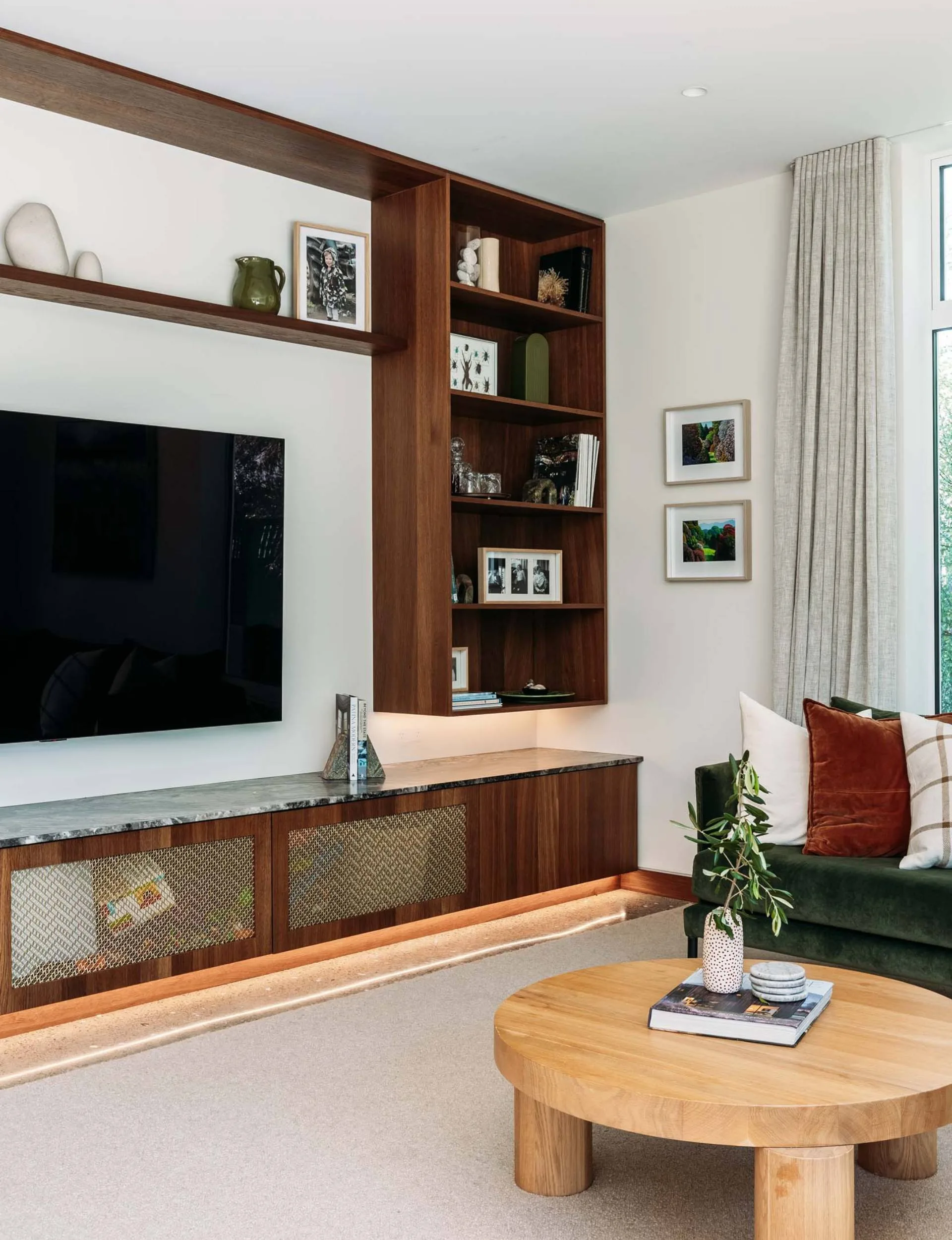 A large oak bookshelf mounted around the TV in the renovated Wellington living room