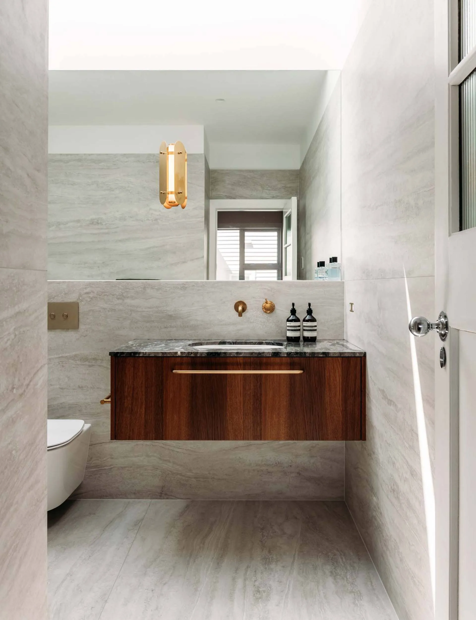 a marble bathroom with an oak vanity