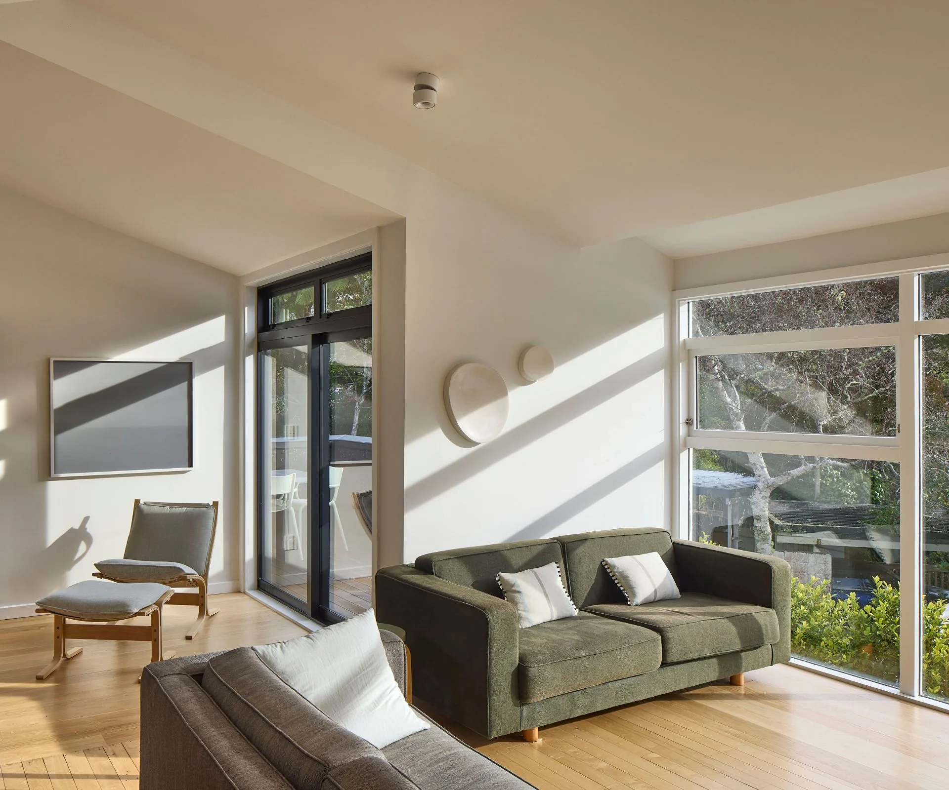 The sliding doors and windows finished in Matt Flax Pod, complements the charred larch cladding on the new modernist extension in this Khandallah home
