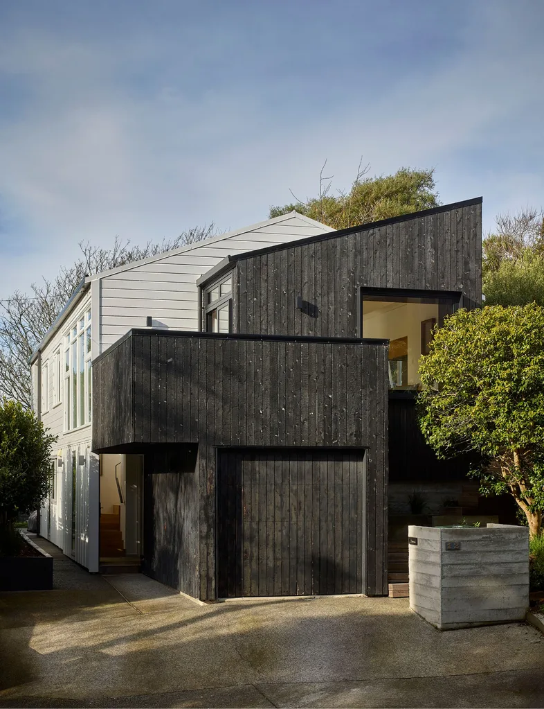 An extension of charred larch to the front of the original light-coloured Khandallah house