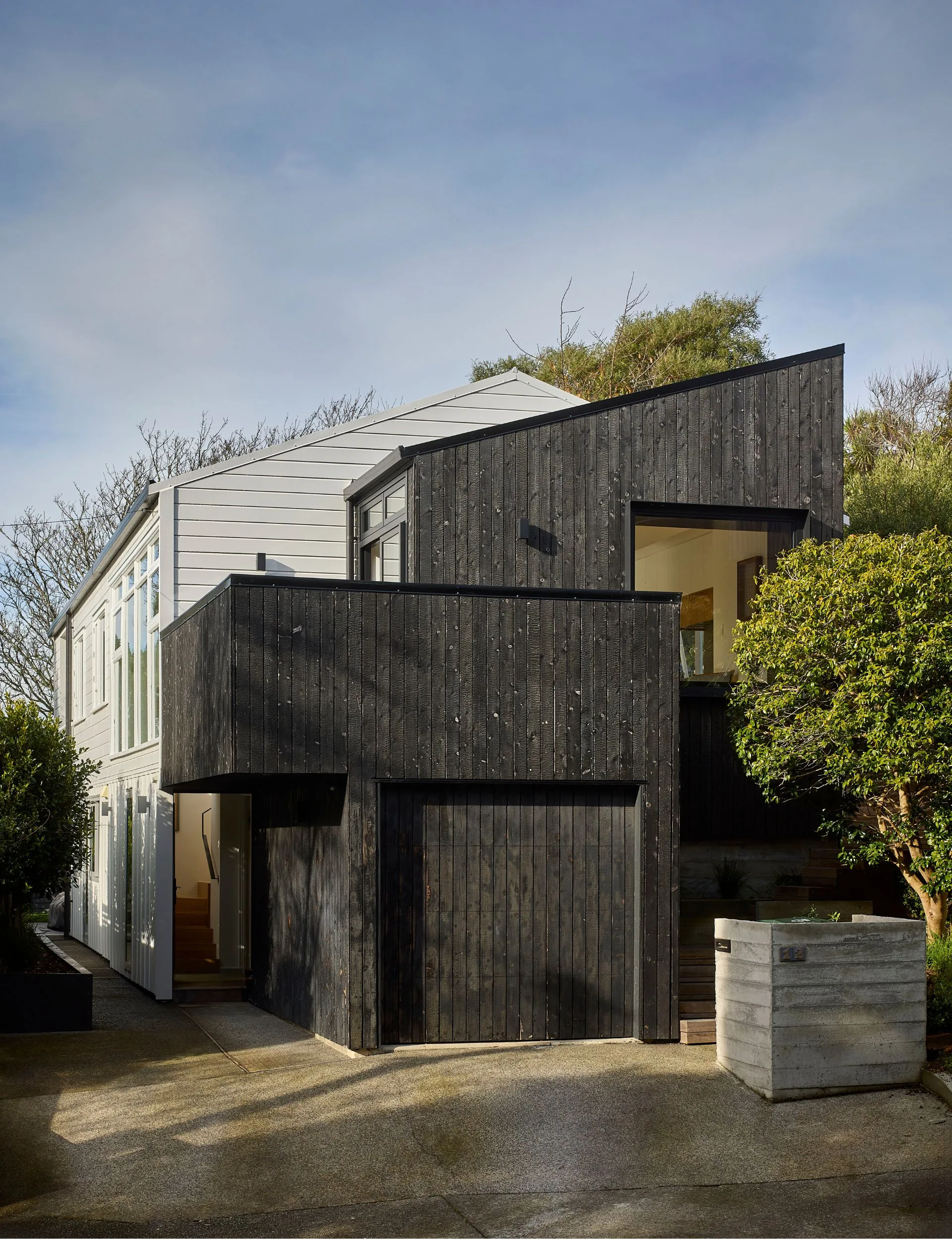 An extension of charred larch to the front of the original light-coloured Khandallah house