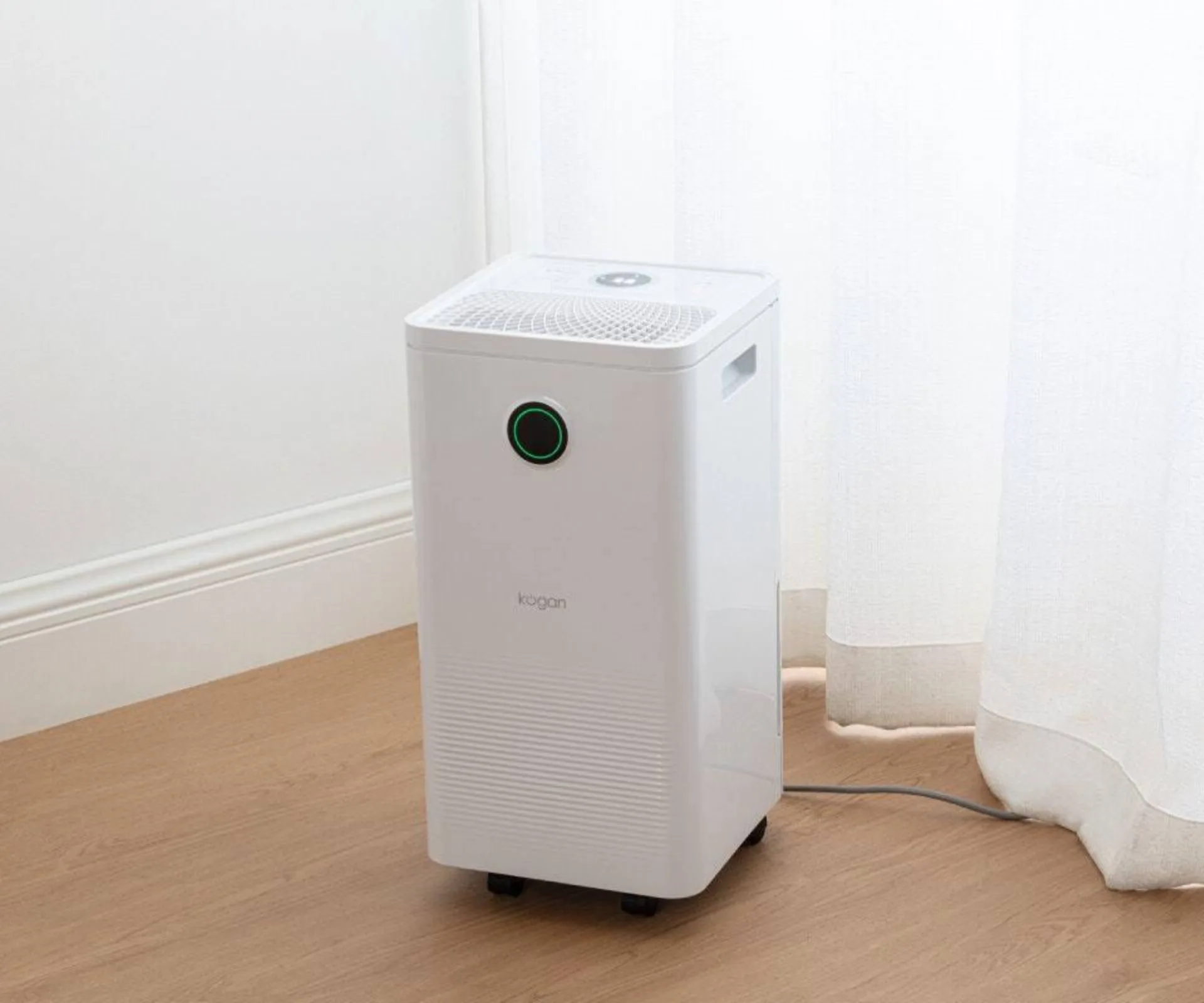 Kogan SmarterHome dehumidifier and air purifier in room with wooden floor and sheer curtain