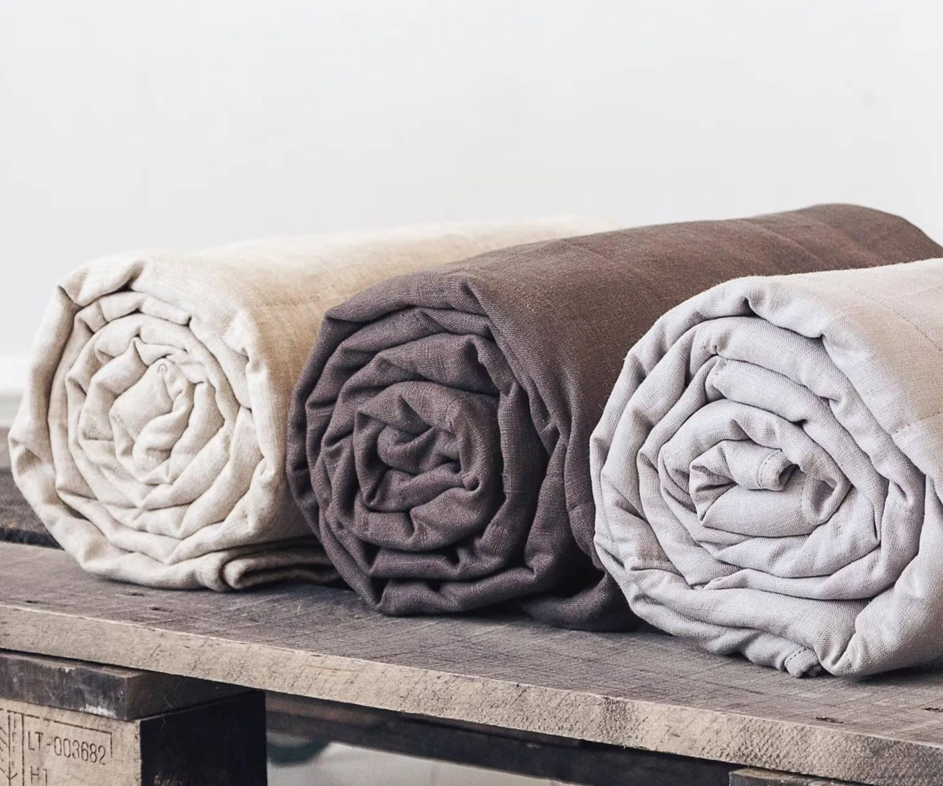Rolled up linen weighted blankets on wooden pallet