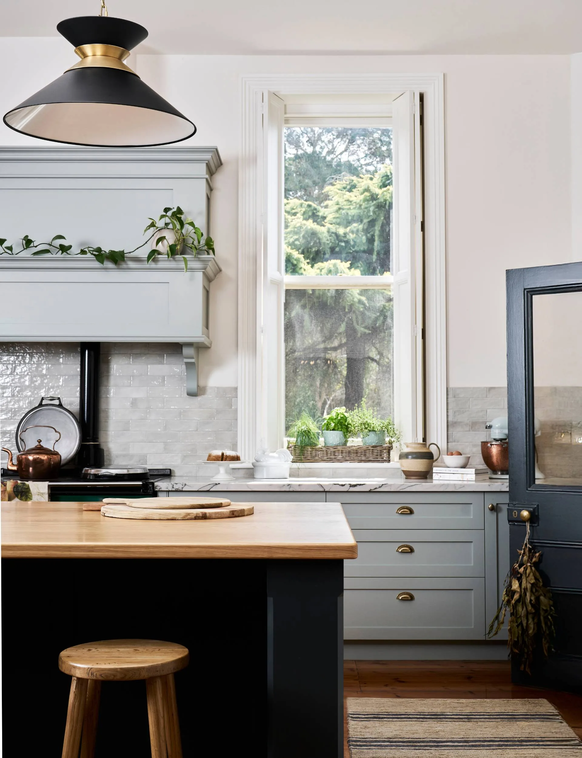 Portrait image of a kitchen with a wooden island and blue cabinets 