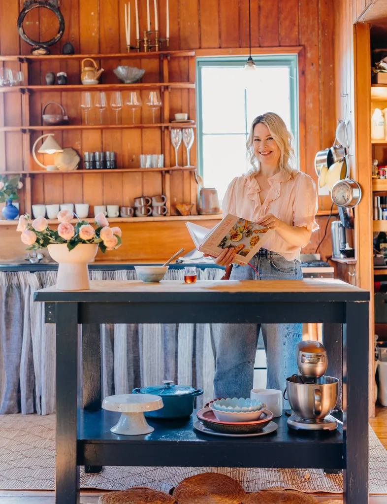 Gretchen Lowe standing in kitchen with cook cookbook and flowers