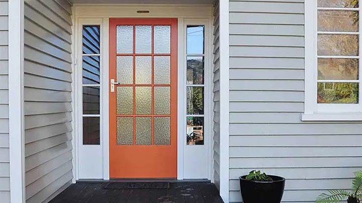 Orange painted front door creates impactful kerb appeal against this white home