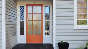 Orange painted front door creates impactful kerb appeal against this white home