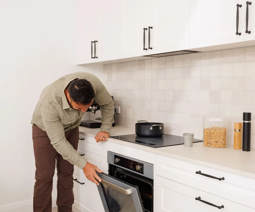 Liam opening the Haier 60cm 500 Series Built in Oven in his new white kitchen