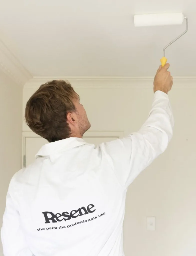 Man in Resene overalls painting the ceiling in Resene Alabaster