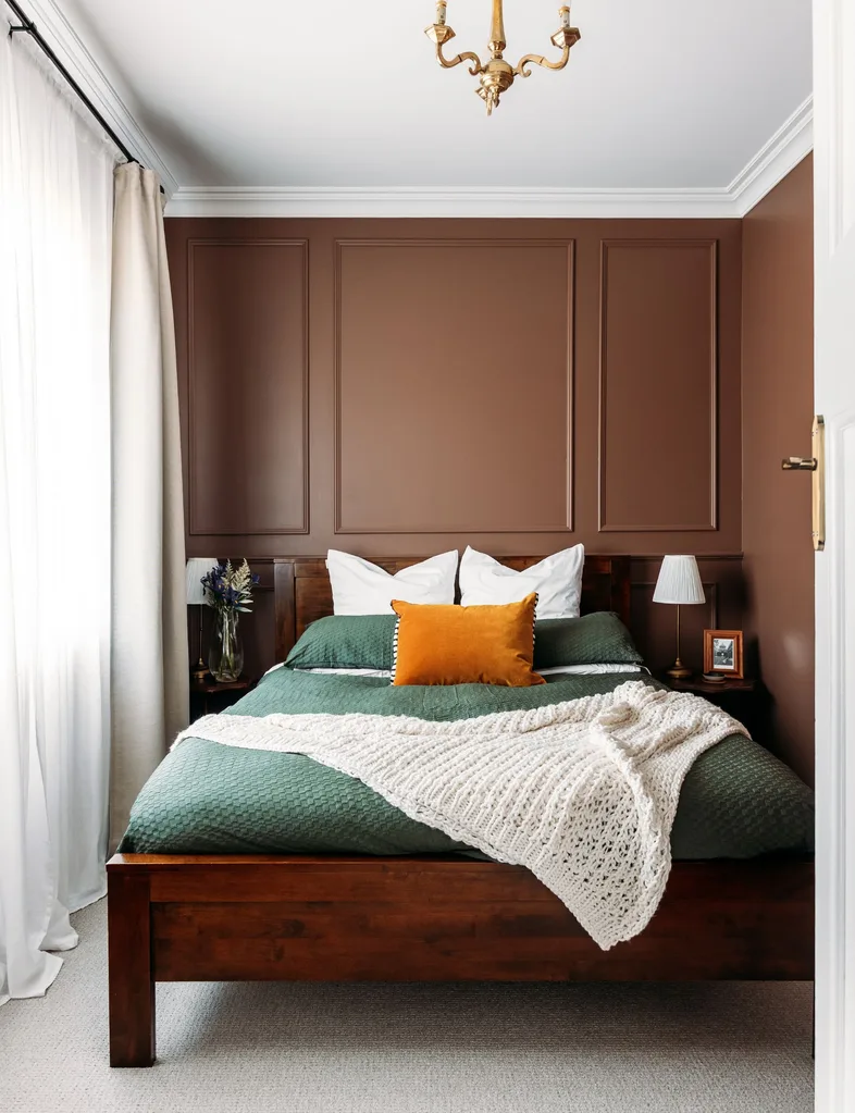 The master bedroom in this Wellington villa has been painted a bold nutmeg brown with white, orange and green accents in the decor