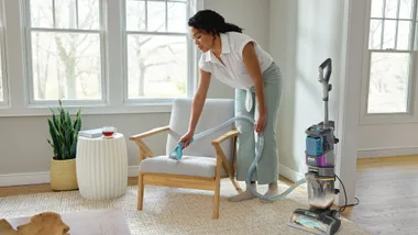 Woman cleaning stain on chair using CarpetXpert HairPro Pet with StainStriker