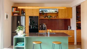 The wooden kitchen in this central Auckland home is contrasted by the green painted on the island