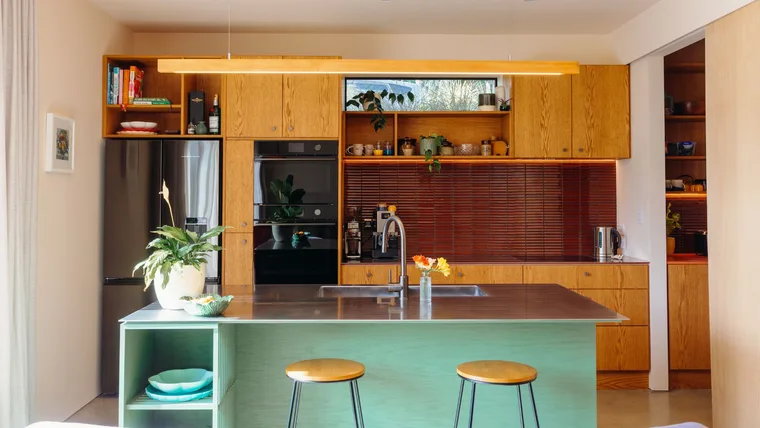 The wooden kitchen in this central Auckland home is contrasted by the green painted on the island