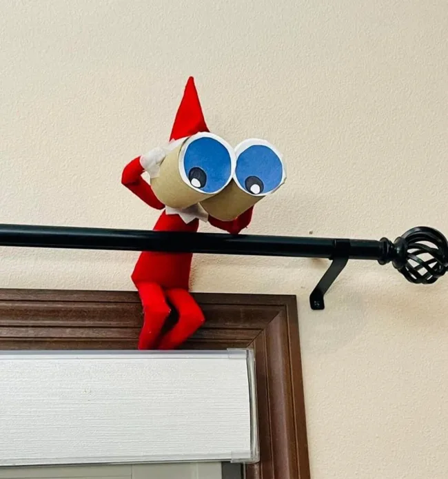 Elf on the Shelf using toilet paper rolls as binoculars