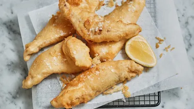 Pieces of fish made using the beer batter recipe - perfectly golden and served with salt and a lemon cheek.