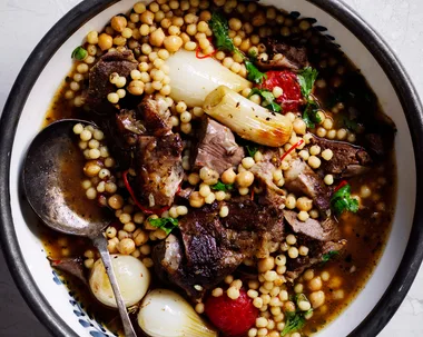 bowl of Baharat lamb shoulder with pearl onions and mogbrabich giant couscous recipe