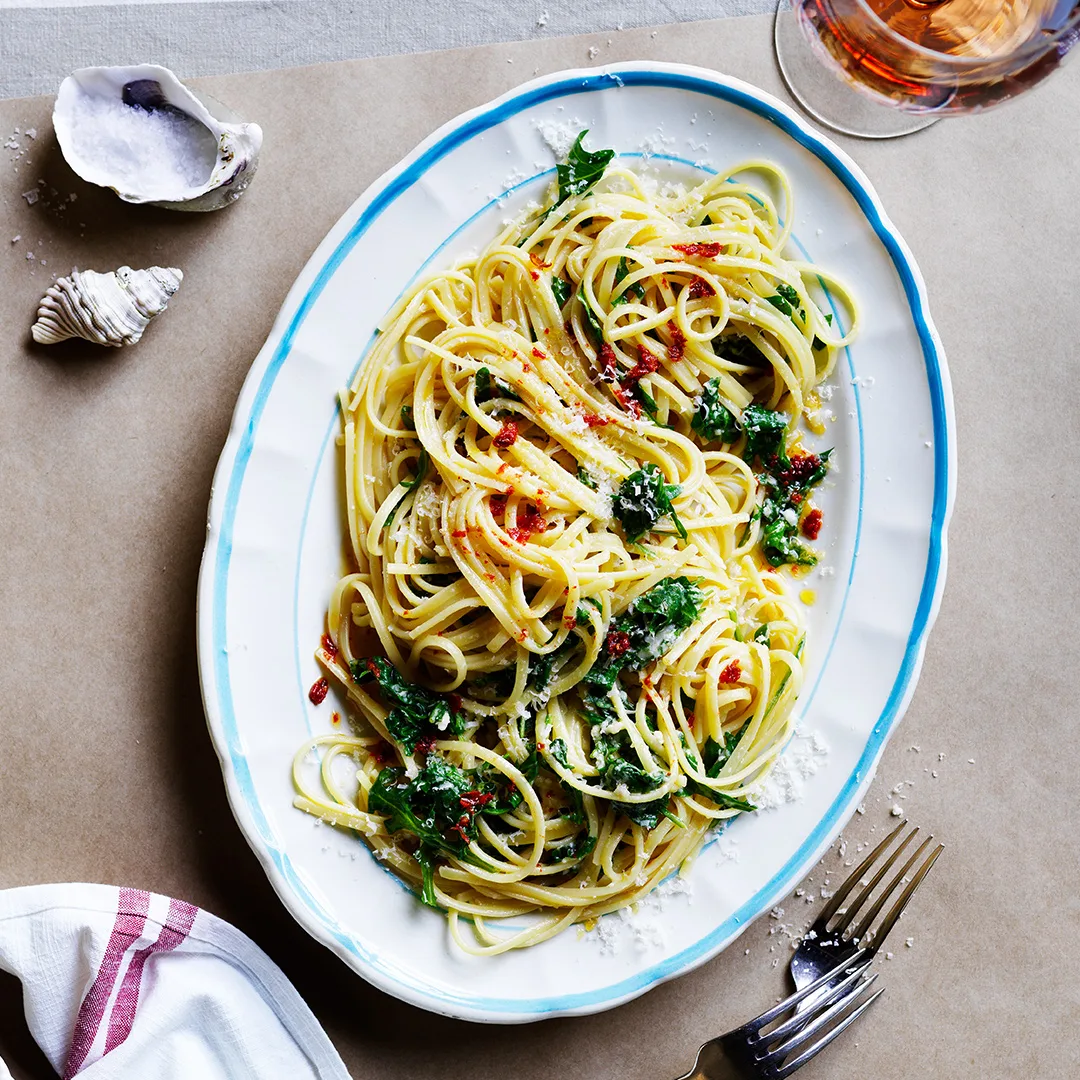 Linguine with lemon chilli and parmesan on white and blue serving platter.