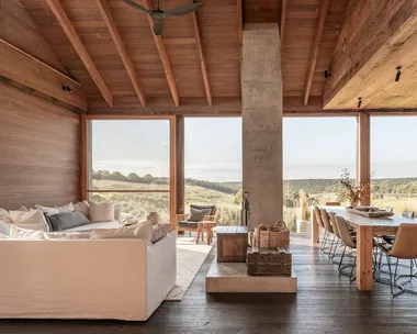 Airbnb Victoria interior featuring open-plan living room with fireplace and adjacent dining room, with views out to rolling hills