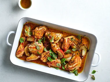 Cider-braised chicken recipe with Brussels sprout and apple salad in white dish.