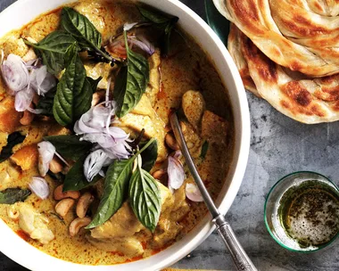 Thai chicken curry with roti with large bowl of chicken, smaller bowl with rice and curry and roti on plates.