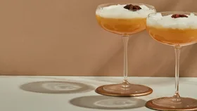Two smoking camel cocktails garnished with star anise on rust backdrop.