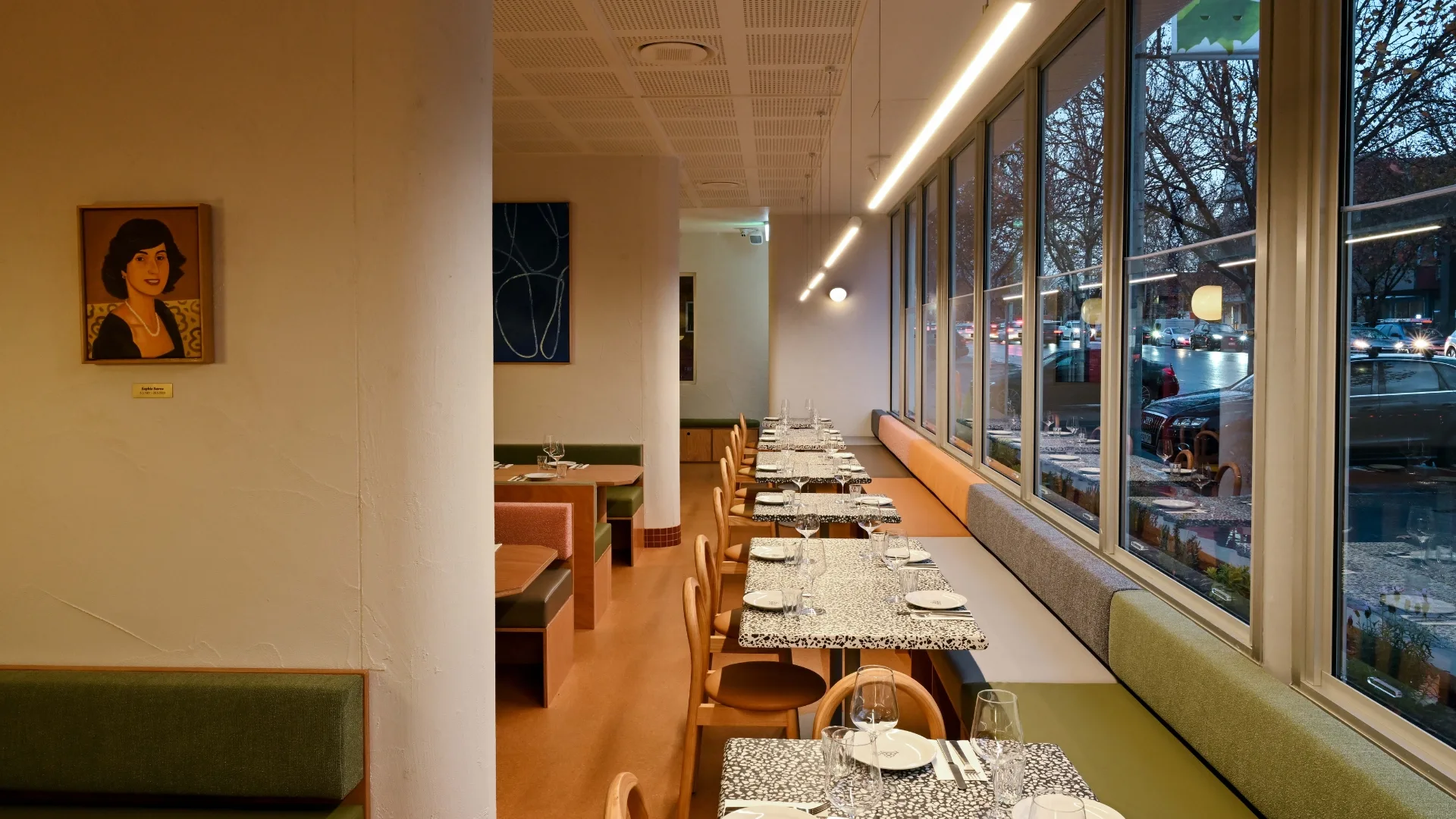 A view of the dining room at Sofia, with a banquette on the right-hand side and a portrait on the wall.