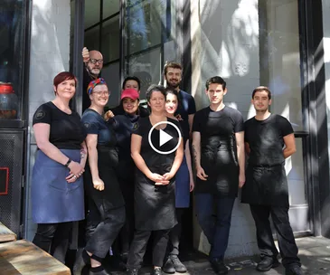O Tama Carey, chef-owner of Sydney's Lankan Filling Station, dressed in a black T-shirt, pouring batter 