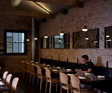 Chef Victor Liong sitting alone in an empty dining room. 