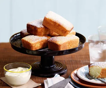 Rectangular lemon cakes piled onto a black cake stand.