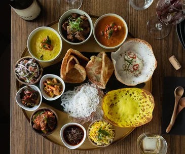 Over-the-top shot of a thali laden with hoppers and small bowls of curries, dhal and pickles.