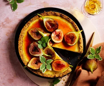 Cheesecake topped with halved figs and golden-orange syrup.