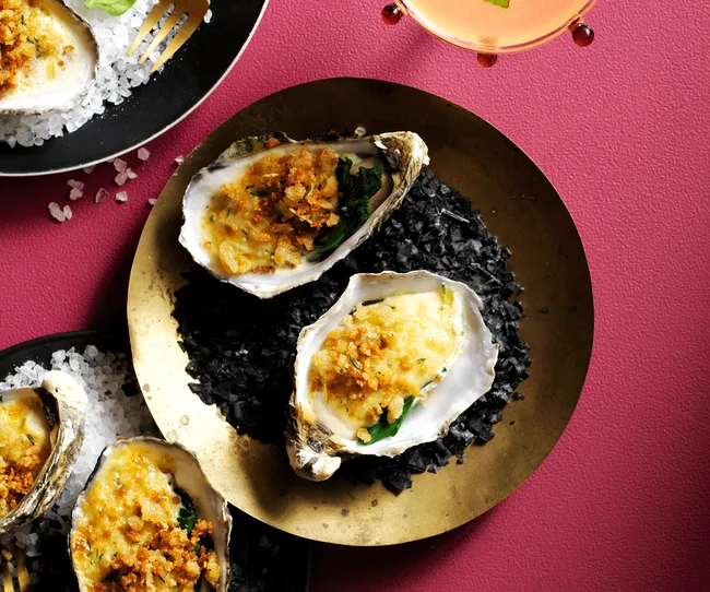 A brass plate with two oysters in their shells made Rockefeller style.