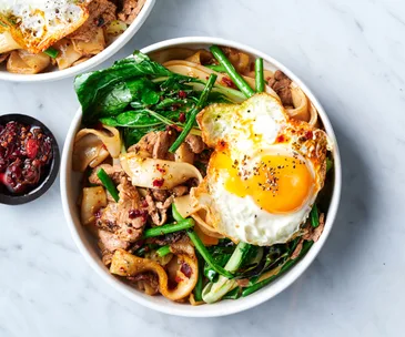 bowl of Cambodian noodle dish lort cha with Asian greens and fried egg