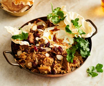 Chicken biryani topped with papadums and herbs
