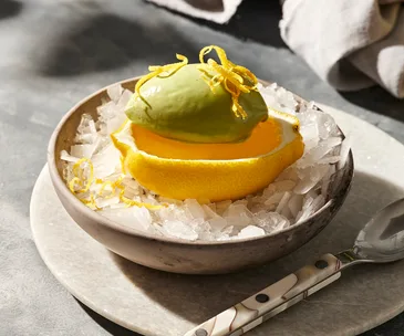A side shot of a lemon jelly served a shallow lemon shell with a scoop of sorrel-yoghurt sorbet on top.