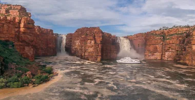 A cruising ship under a waterfall in The Kimberley region of Australia