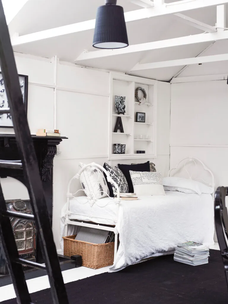 Black and white studio with daybed and ornamental fireplace.