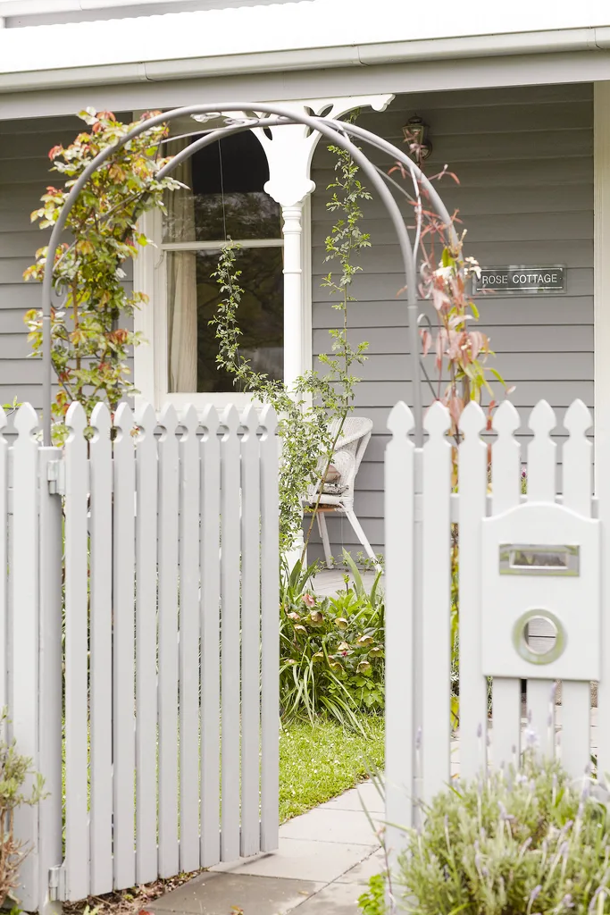 Grey cottage exterior with white picket fence.