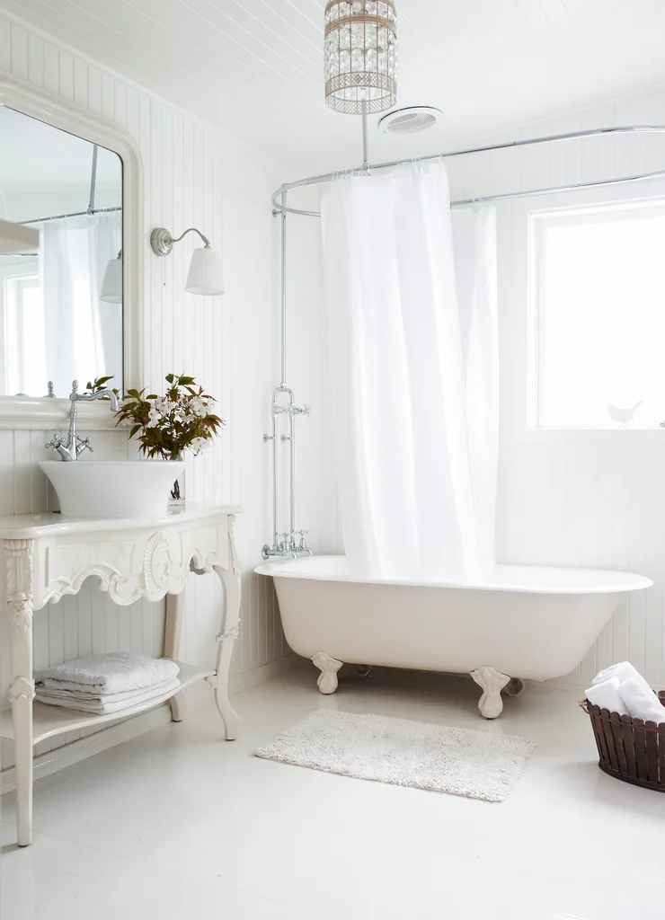 All white bathroom in a cottage with a claw foot cast iron tub.