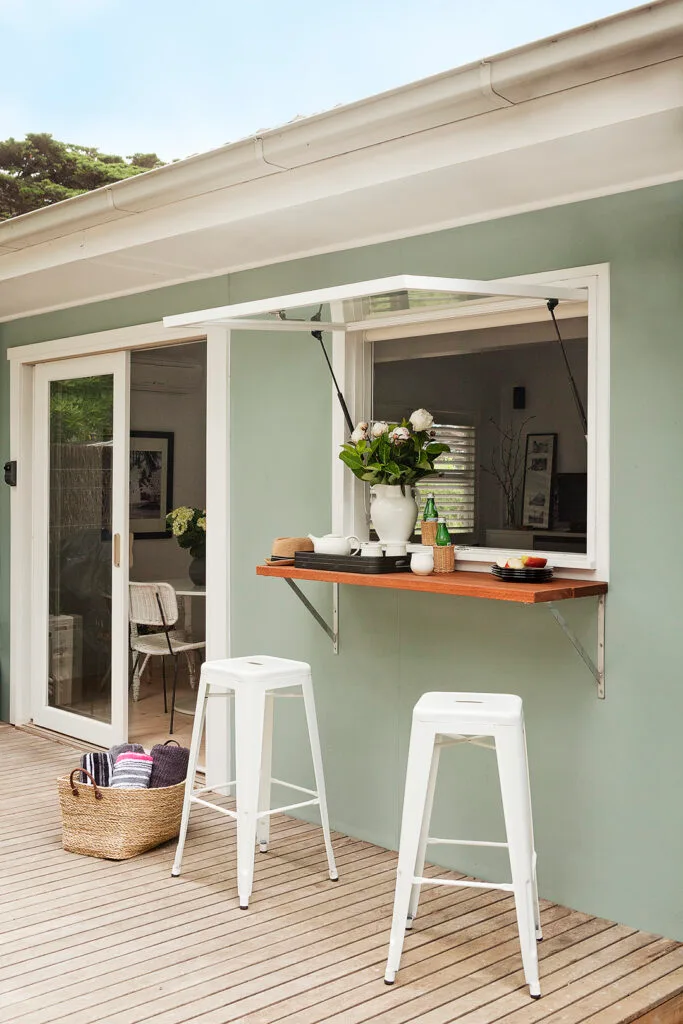 Servery window opening to the deck of a renovated coastal weekender.