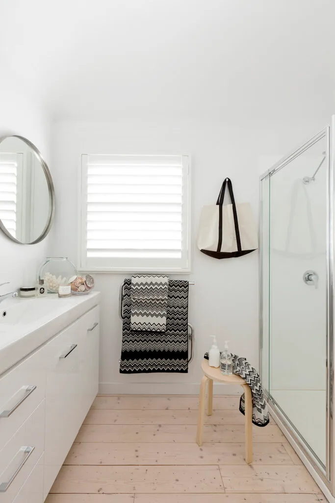 White coastal bathroom with wood-look flooring.